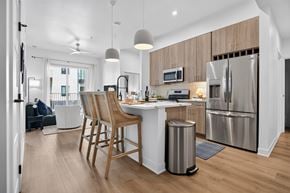 Bentonville apartment for rent - A modern kitchen with wooden chairs and stainless steel appliances.