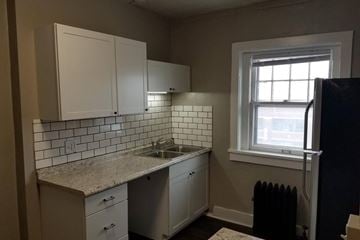 Omaha apartment for rent - A kitchen with white cabinets and a tiled backsplash.