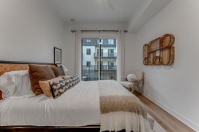 Bentonville apartment for rent - A bedroom with a large bed and a view of a building outside the window.
