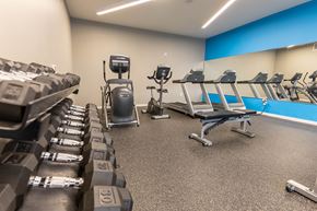 Omaha apartment for rent - A gym with a row of treadmills and dumbbells.