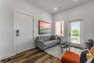 Bentonville apartment for rent - A modern living room with a grey sofa and a painting on the wall.