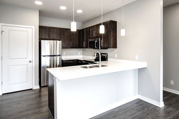 Omaha townhouse for rent - A kitchen with a white island and dark brown cabinets.