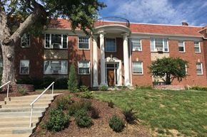 Omaha apartment for rent - the front of a brick building with stairs and a tree