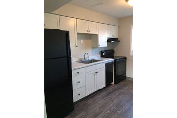 Omaha apartment for rent - a kitchen with white cabinets and a black refrigerator
