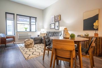 Allentown apartment for rent - A living room with a grey couch, a wooden table and chairs, and a rug with a zigzag pattern.