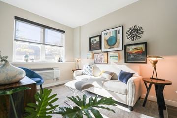 Allentown apartment for rent - A living room with a white couch, a blue chair, and a table with a vase on it.