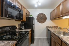 Emmaus apartment for rent - A kitchen with black appliances and wooden cabinets. at Meadows Apartments, Emmaus, 18049