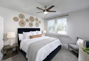 Houston apartment for rent - a bedroom with a queen-sized bed, ceiling fan, and windows at a senior apartment community