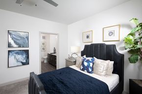 Rowlett apartment for rent - a bedroom with a queen-sized bed and ceiling fan at a senior apartment community