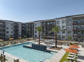 Chandler apartment for rent - a swimming pool with palm trees in front of an apartment building