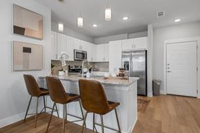 Kyle apartment for rent - a kitchen with stainless steel appliances, granite countertops, and countertop seating at a senior apartment community