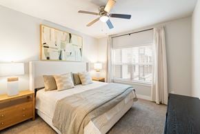 San Antonio apartment for rent - A bedroom with a bed, nightstand, and a painting on the wall.