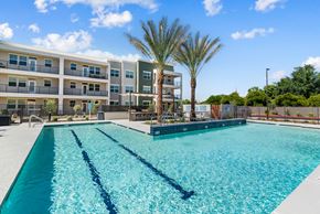 Mesa apartment for rent - A swimming pool in front of a multi-story apartment building.