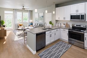 Naples apartment for rent - an open concept kitchen and living room with stainless steel appliances and white cabinets at a senior apartment community