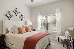 Houston apartment for rent - A bedroom with a large bed and a window with blinds.