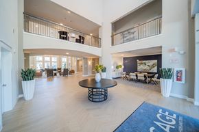 Charlotte apartment for rent - A spacious lobby with a blue rug that reads "AGE" and a large black table in the center.