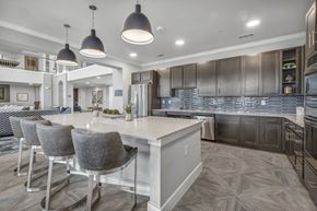 Katy apartment for rent - a communal clubhouse kitchen with a large island and chairs at a senior apartment community
