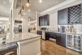 Houston apartment for rent - a communal clubhouse kitchen with a large island and chairs at a senior apartment community