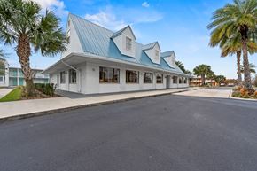 Melbourne apartment for rent - A white building with a blue roof is surrounded by palm trees.