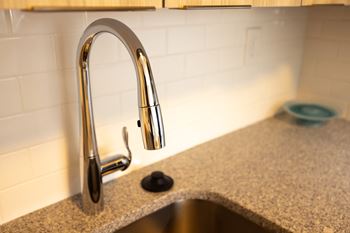 A kitchen sink with a chrome faucet on a granite counter top