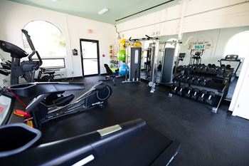 A gym with cardio equipment and weights on the floor