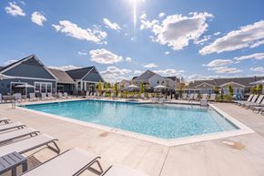 Mason apartment for rent - A large outdoor swimming pool surrounded by sun loungers and a building in the background.