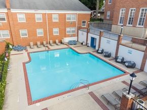 Grand Rapids apartment for rent - A large swimming pool surrounded by a brick building and lounge chairs.