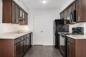 East Lansing townhouse for rent - A kitchen with dark wood cabinets and a black refrigerator.