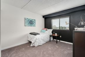 East Lansing apartment for rent - A bedroom with a bed, nightstand, and a window.