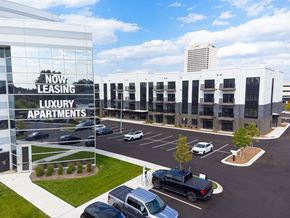 Troy apartment for rent - A parking lot in front of a building with the words "Now Leasing Luxury Apartments" on the side.
