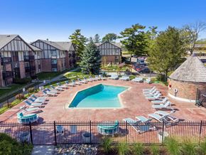 East Lansing apartment for rent - A pool surrounded by chairs and trees in front of apartment buildings.