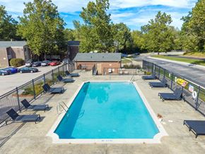 Okemos apartment for rent - A large outdoor swimming pool surrounded by a fence and lounge chairs.