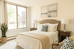 East Lansing apartment for rent - A bedroom with a large bed and a potted plant.