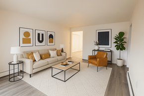 Lansing apartment for rent - A living room with a white couch, a coffee table, and a chair.