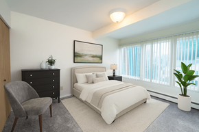 East Lansing apartment for rent - A bedroom with a large bed, a chair, and a painting on the wall.
