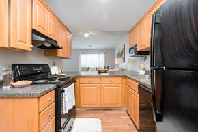 East Lansing apartment for rent - A kitchen with wooden cabinets and black appliances.