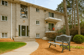 East Lansing apartment for rent - A bench is in front of a building with a tree to the right.