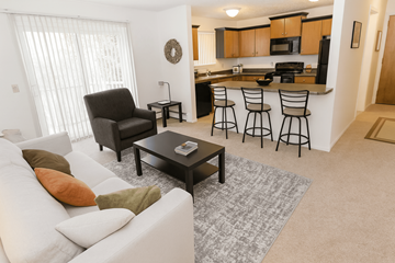 East Lansing apartment for rent - A living room with a white couch and a black chair.