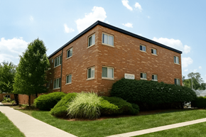 East Lansing apartment for rent - A red brick building with a green bush in front.