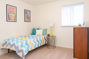 East Lansing apartment for rent - A bedroom with a bed, nightstand, and two pictures on the wall.