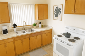 East Lansing apartment for rent - A kitchen with a white stove and wooden cabinets.