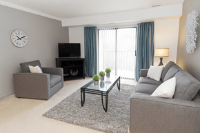 East Lansing apartment for rent - A living room with a grey couch, a black coffee table, and a grey armchair.