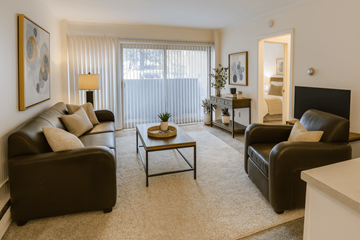 East Lansing apartment for rent - A living room with brown leather furniture and a large window with blinds.
