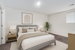 East Lansing townhouse for rent - A bedroom with a large bed and a plant on the side table.