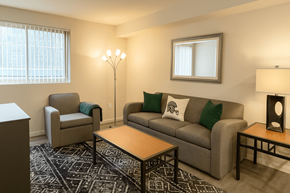 East Lansing apartment for rent - A living room with a grey couch, a chair, a coffee table, and a lamp.