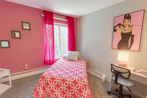 East Lansing apartment for rent - A bedroom with a pink wall and a bed with a pink and white comforter.
