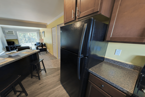 East Lansing apartment for rent - A black refrigerator is in a kitchen with wooden cabinets.