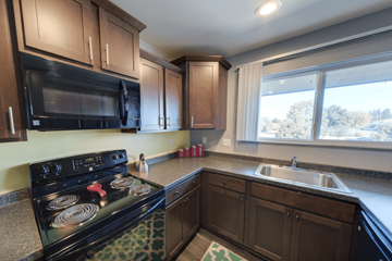 East Lansing apartment for rent - A kitchen with a black stove top oven and wooden cabinets.
