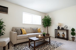 Okemos apartment for rent - A living room with a beige couch, a coffee table, and a potted plant.