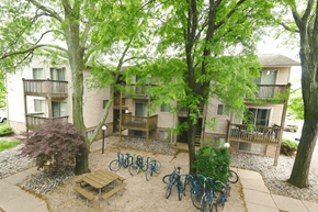 East Lansing apartment for rent - A courtyard with bicycles and a bench surrounded by trees.